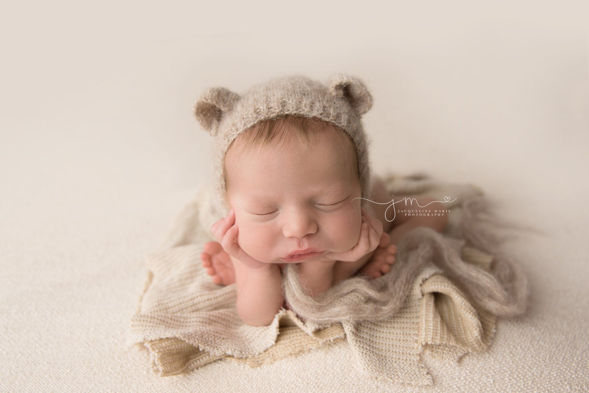 newborn baby boy wears teddy bear bonnet for froggy pose in columbus ohio