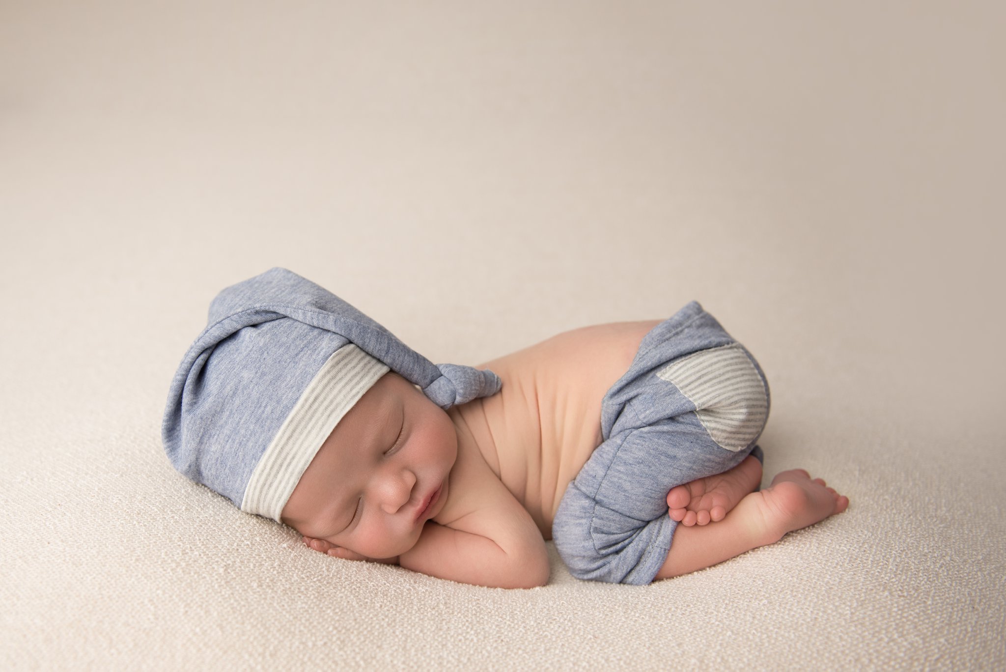 columbus ohio newborn photographer poses baby boy in blue and gray pants and hat set for newborn photography session