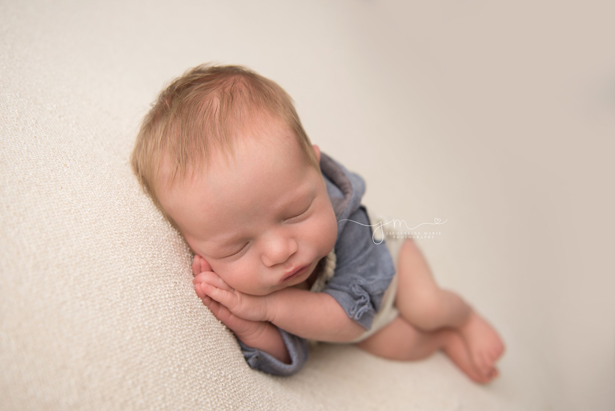 1 week old newborn wears cream and blue hooded romper during newborn photo session
