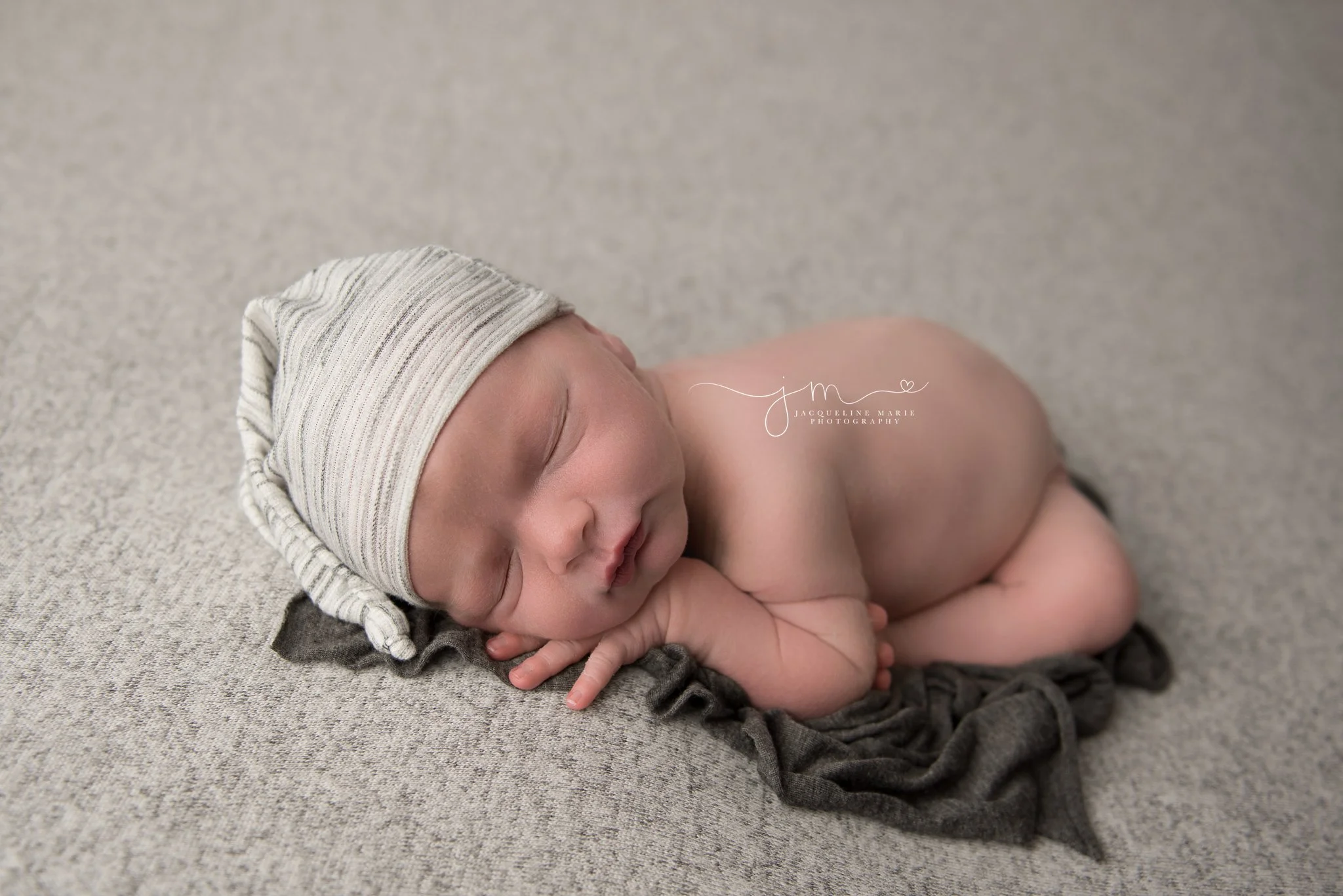 newborn baby boy wears stripe sleepy hat during newborn photography session in columbus ohio