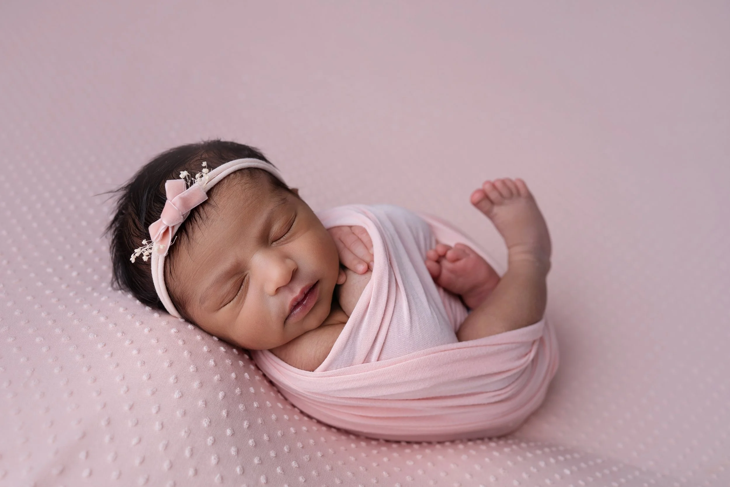 newborn baby girl wears pink bow headband for Columbus Ohio newborn photographer session