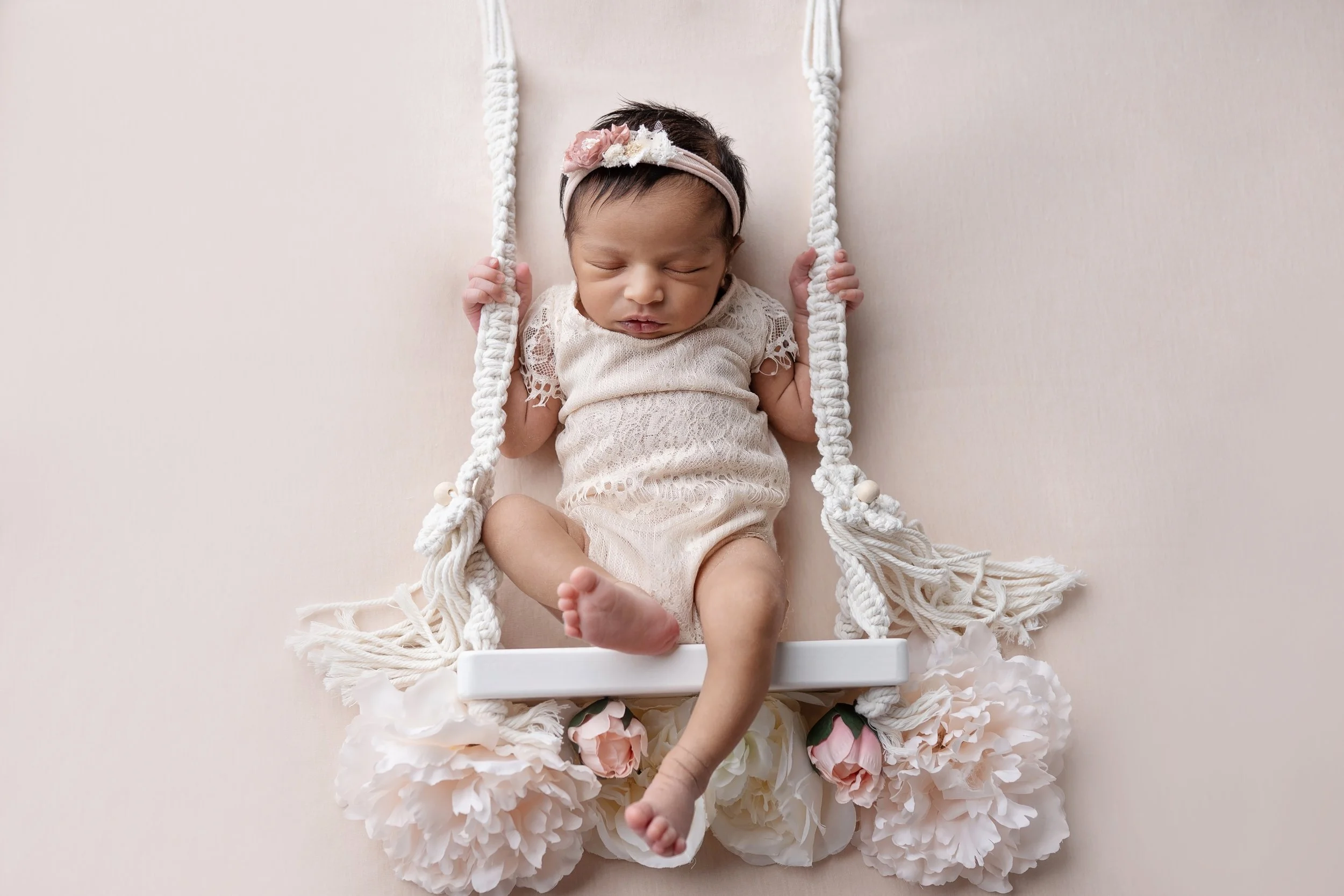 newborn baby girl poses on floral swing for newborn photography in Columbus Ohio