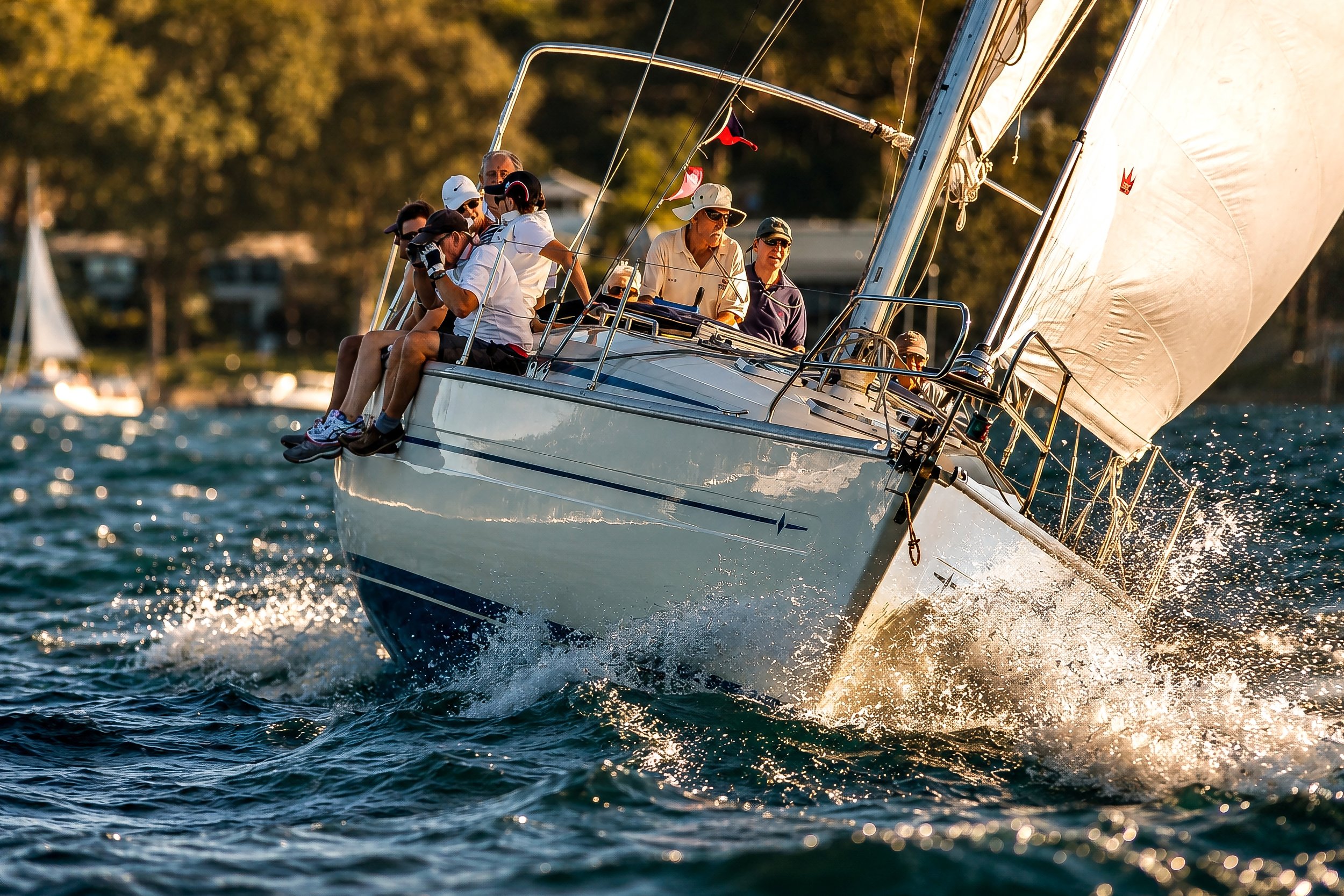A group of people sailing on a sailboat during sunset.