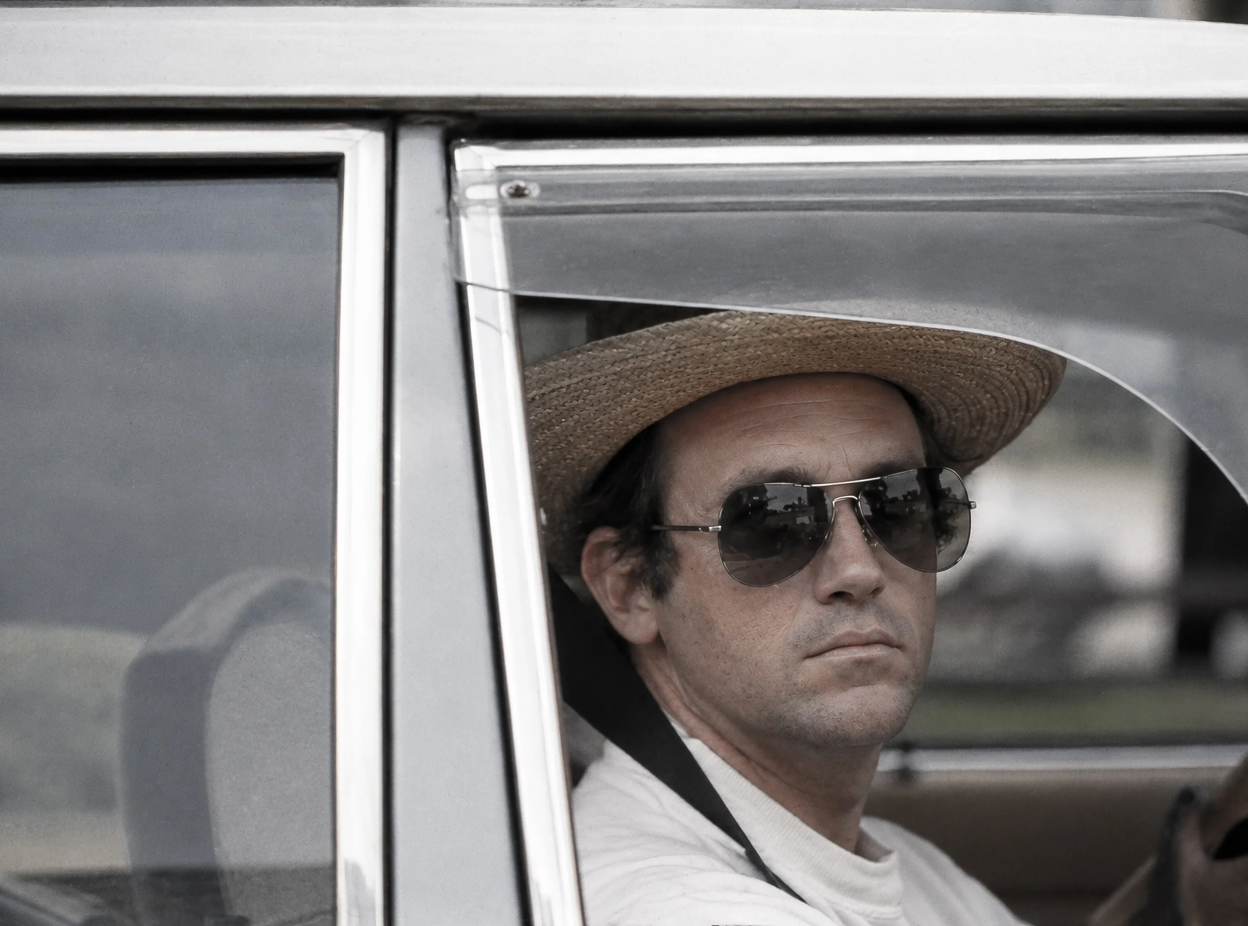 The Man in the Hat - A man wearing a broad-brimmed hat and sunglasses looks directly towards the camera from inside his car. Caught unexpectedly through the side window, the photograph has the immediacy of a fleeting encounter at a Sydney intersectio