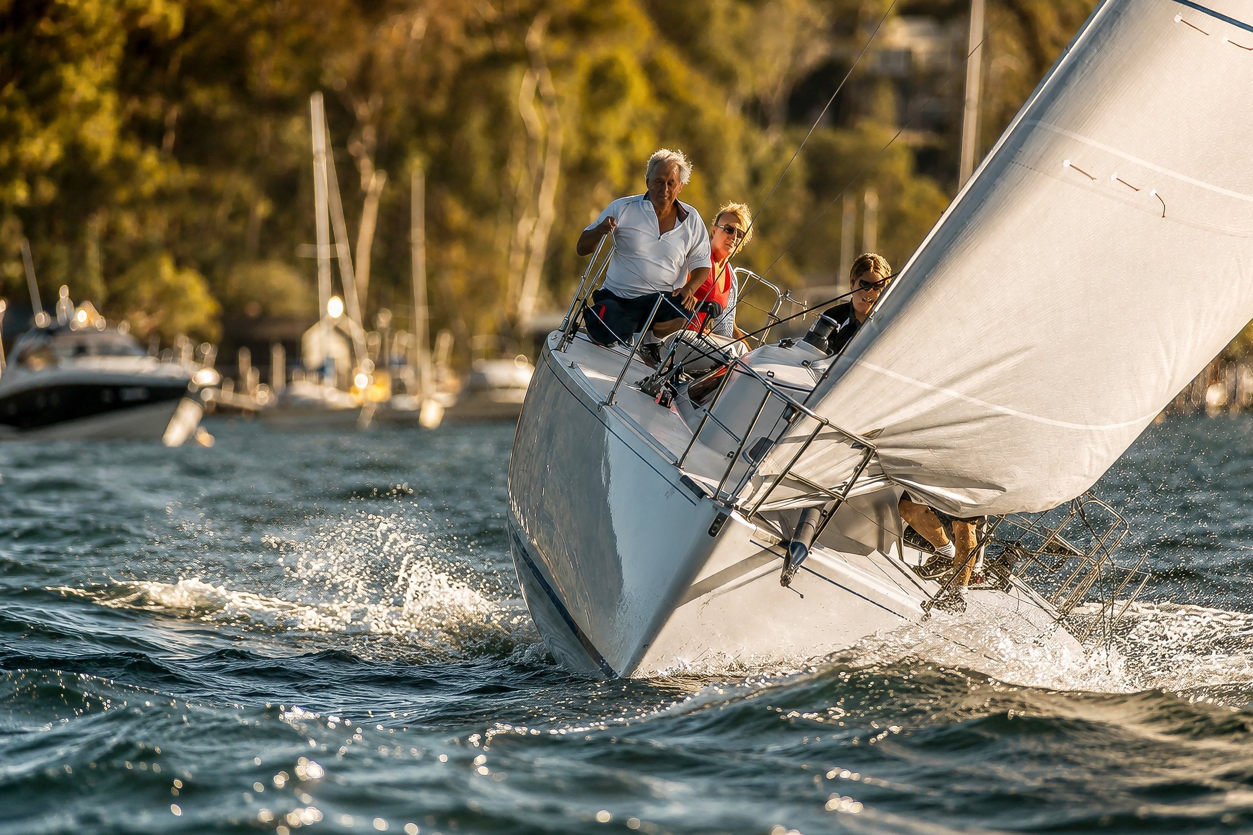Sailboats on the water with people on board.