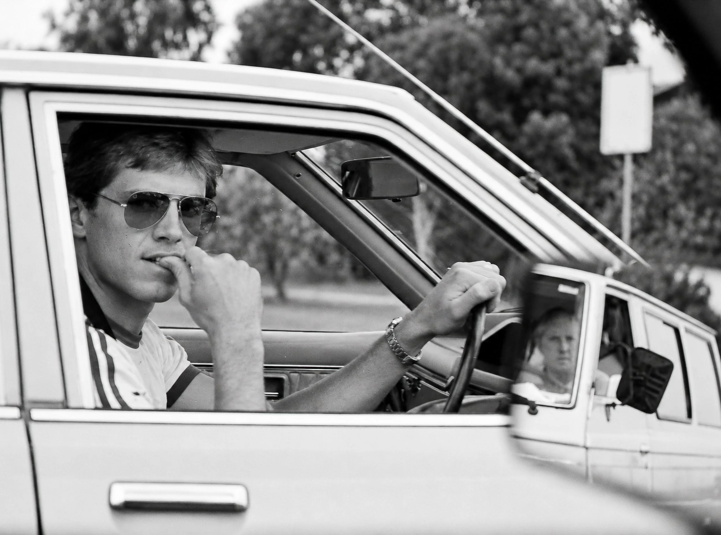 Young Man Driving - The same young man is captured again from a different angle, looking towards the camera while driving. His expression, the car interior and the surrounding traffic combine to create another spontaneous glimpse of Sydney life circa