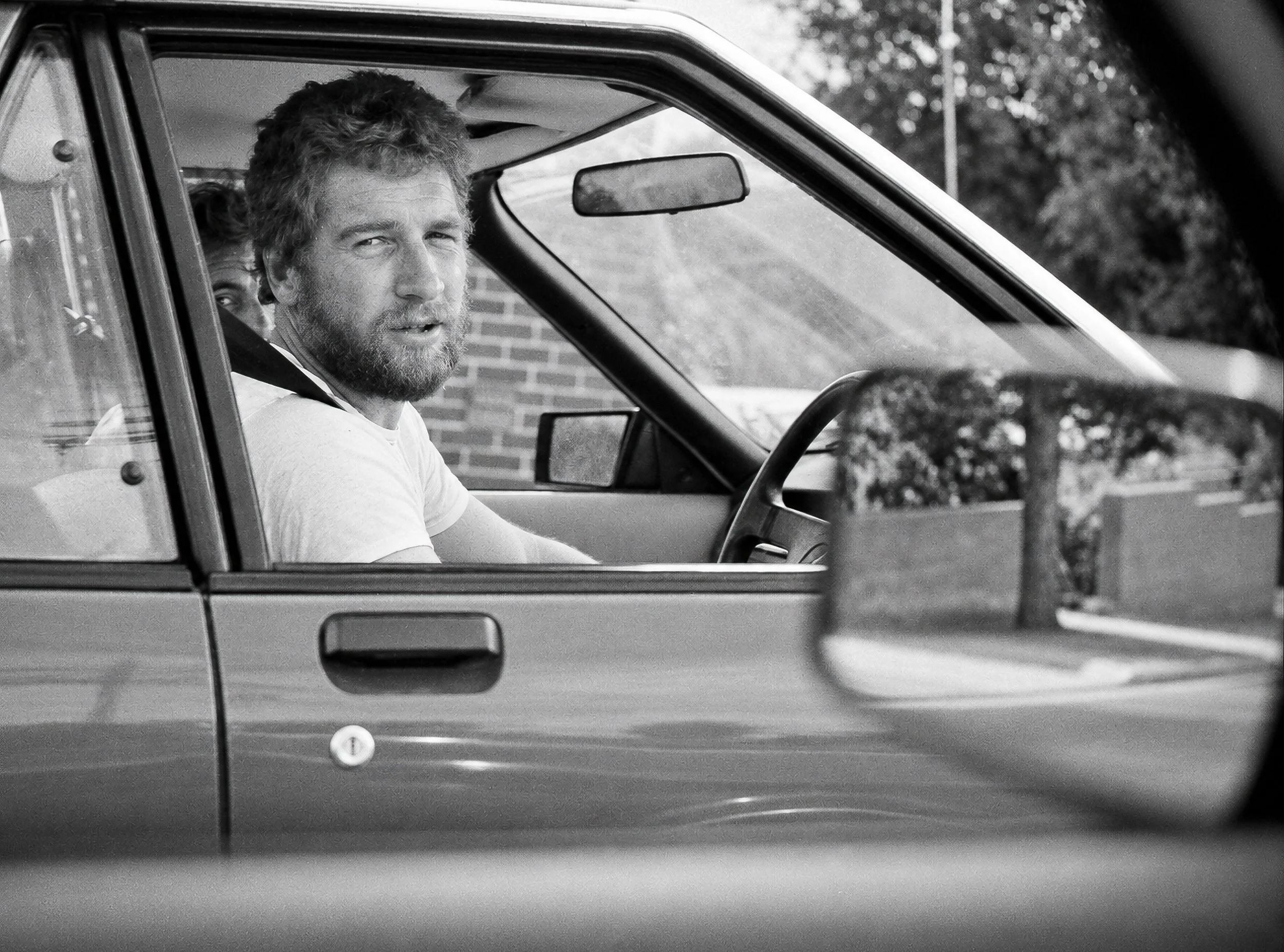 Driver in the Mirror - A bearded driver is captured through the open window of his car The composition turns an ordinary traffic moment into a quietly observed portrait.
