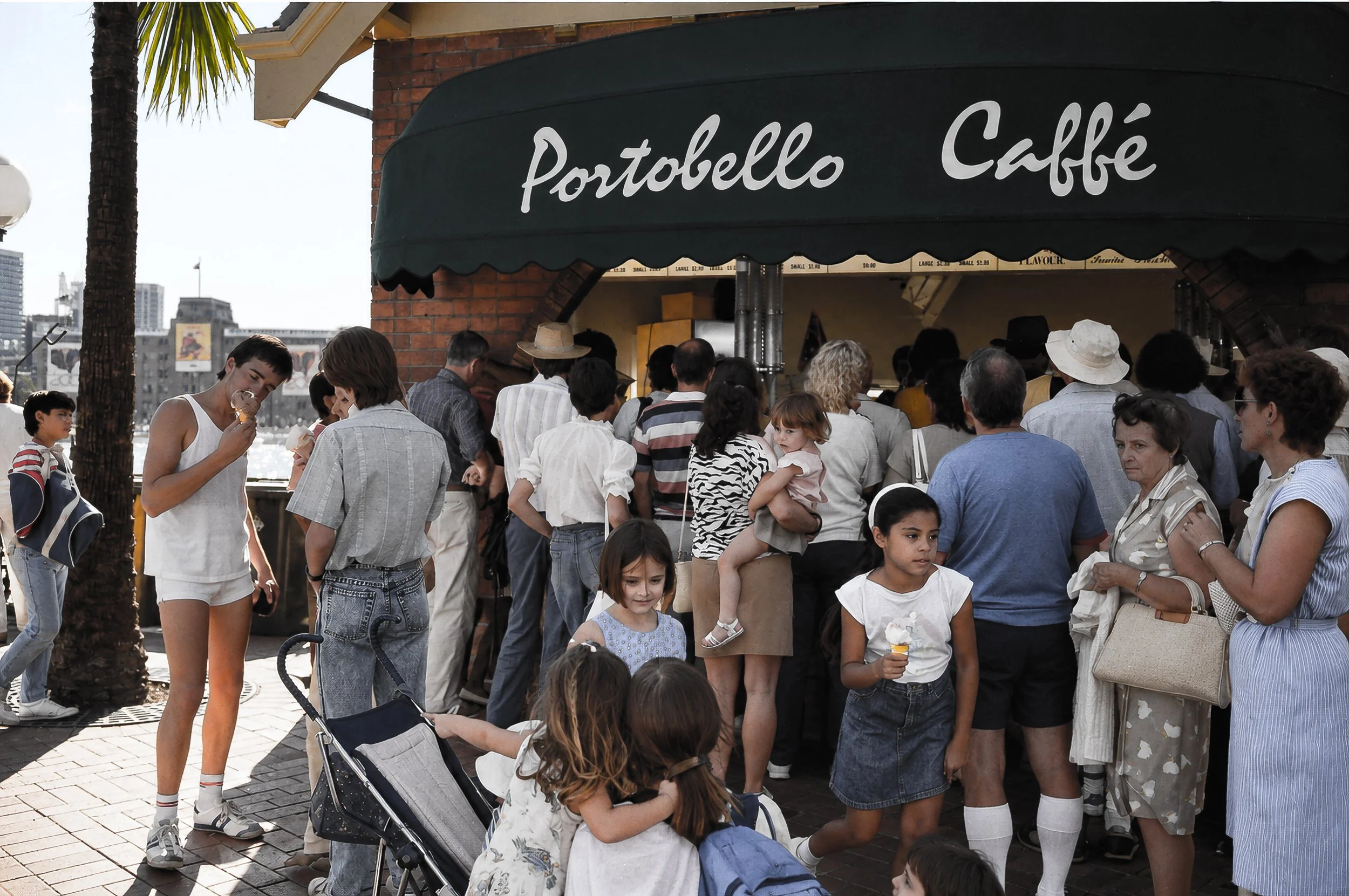 Portobello Caffé - The Crowd - A busy crowd gathers outside Portobello Caffé, with people of different ages and backgrounds filling the waterfront setting. The photograph captures the informal social life of Sydney at street level.