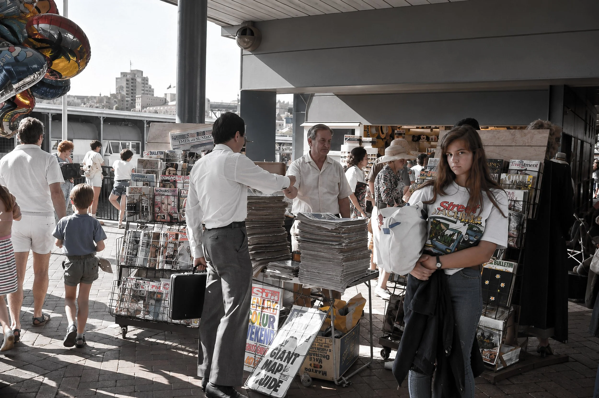 Sydney Newsstand - People gather around a busy newsstand beneath the city's covered walkways. Newspapers, magazines, signs and pedestrians create a richly detailed snapshot of everyday Sydney street life.