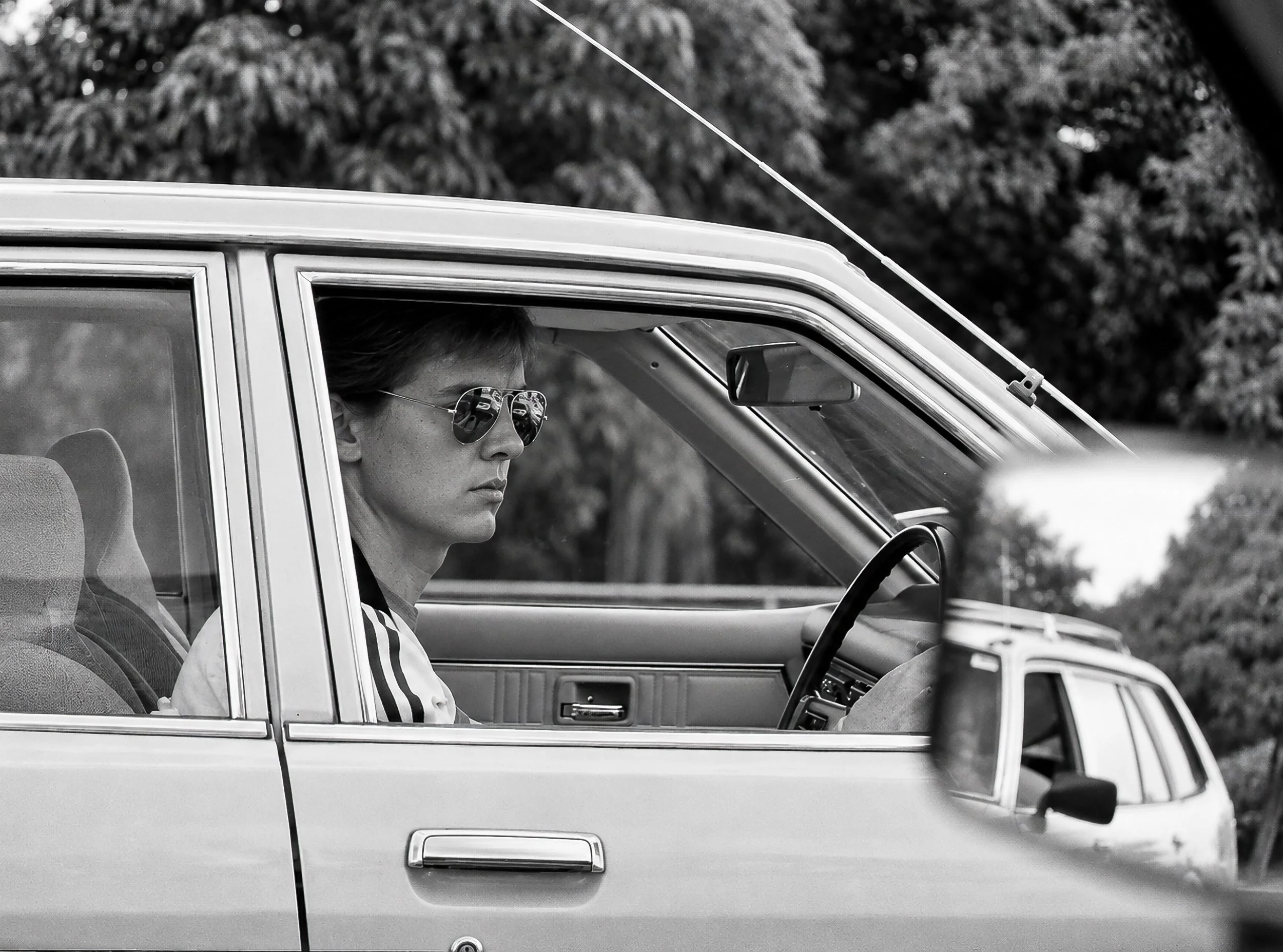 Young Man at the Wheel - A young man is photographed in profile as he drives through Sydney, his face framed by the car window and surrounding vehicle details. The candid composition captures an unposed moment of everyday life in the city during the 