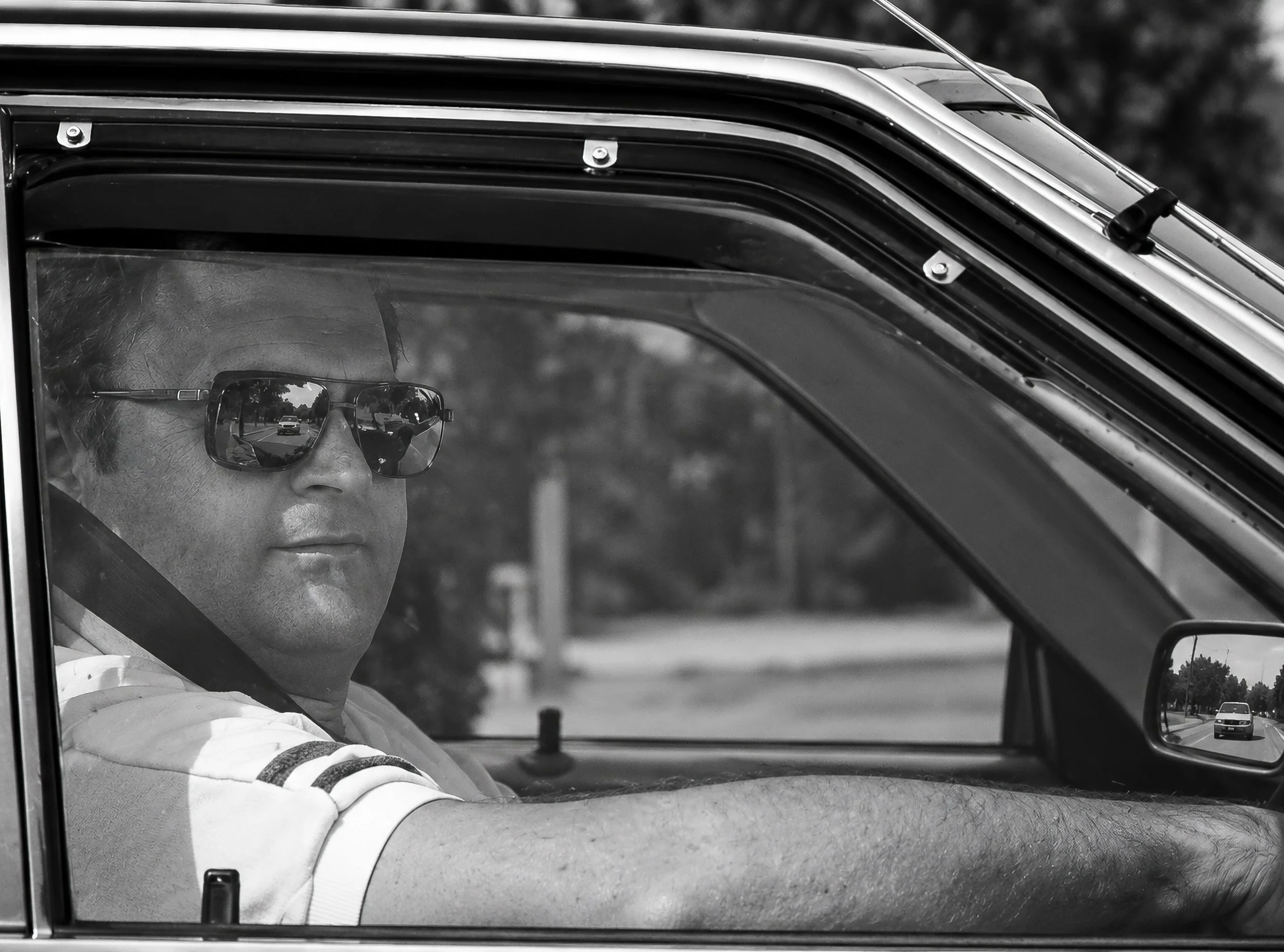 Through the Window - A driver looks towards the camera through the car window, his sunglasses and relaxed posture giving the image a distinctly 1980s character. Reflections across the glass become part of the composition rather than simply an obstruc