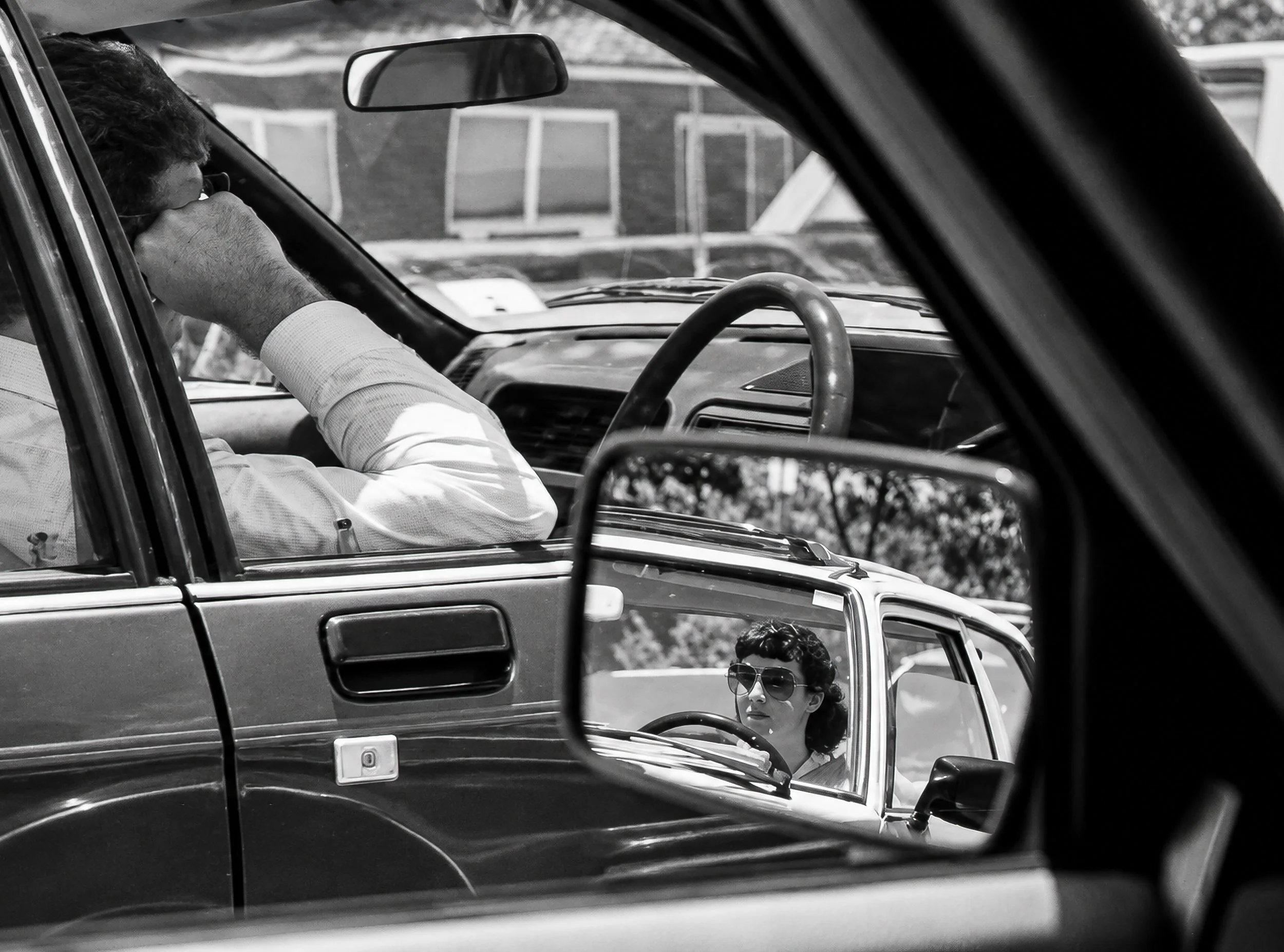 Seen in the Mirror - The driver is partially hidden by the car frame while the wing mirror provides a second view of another vehicle and its occupant. The layered reflections and viewpoints make this one of the more observational photographs in the s