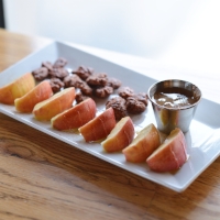 Honeycrisp Snack Plate slices apples topped with honey & cinnamon, served with almond butter and cinnamon pecans