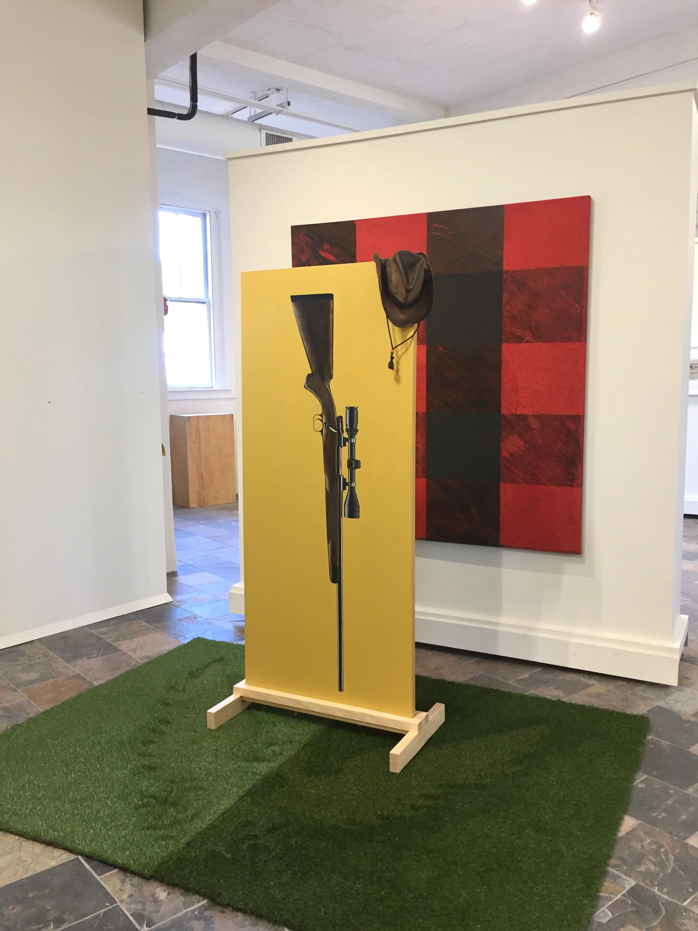 Shown: “After Paul Bunyan and Several Similar Folks Until Ice Cube” (Plaid or Red/BLK Flannel Painting) + “On My Last Strength Against You” (Winchester Rifle) with Hat + “Let the Mighty Eagle Soar” Synthetic Grass