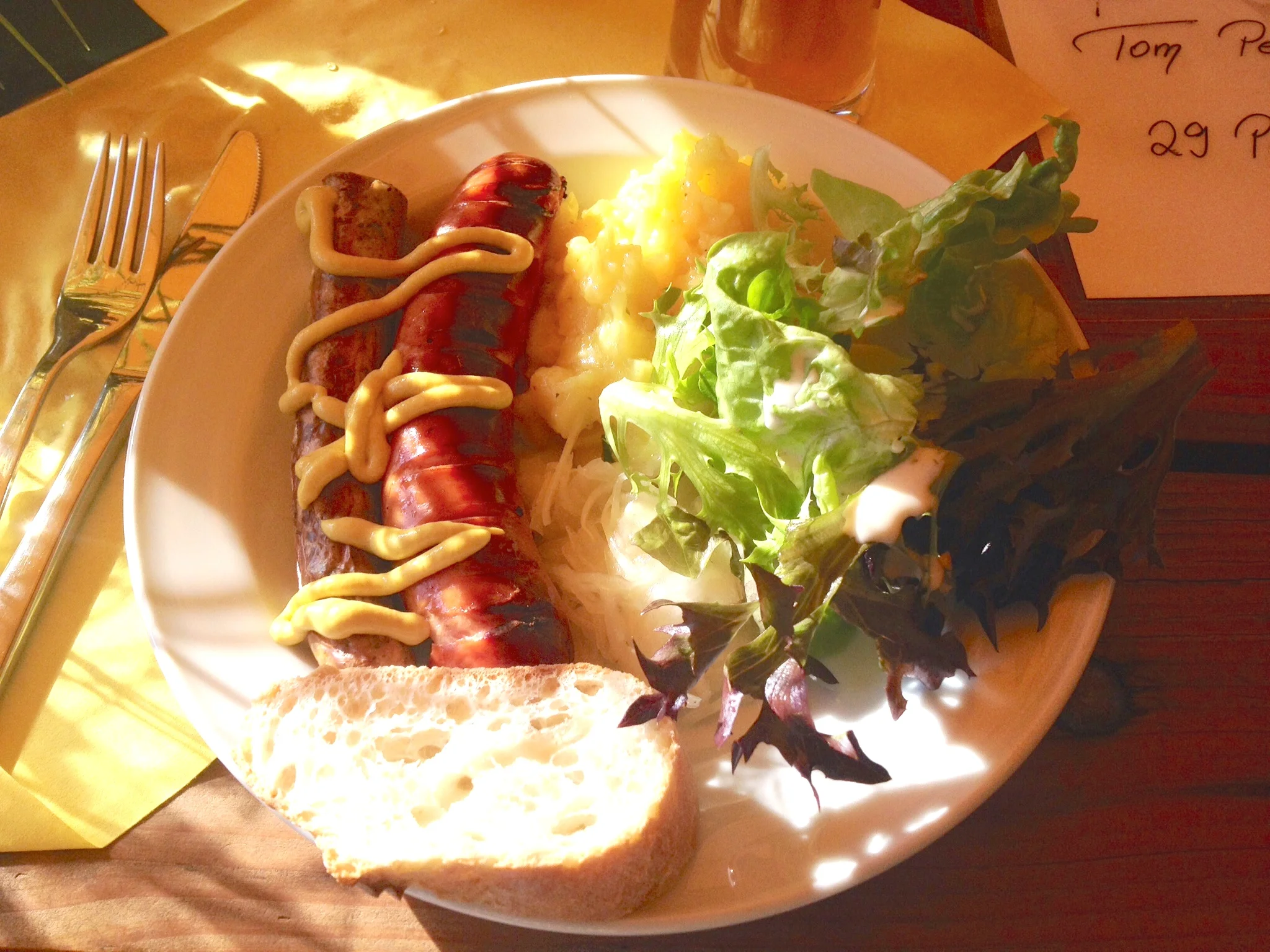 German grill food: Fränkische Bratwurst, Rote Wurst, German potato salad, sauerkraut, salad with yogurt dressing, and a slice of baguette