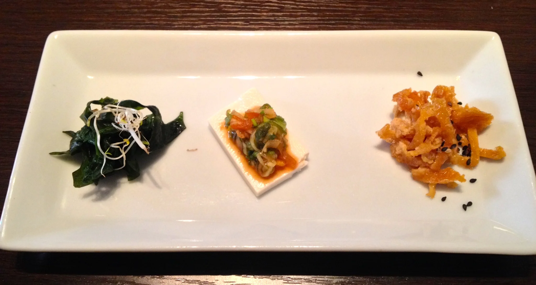 Appetizers from left to right: seaweed salad, soft tofu with a green onion topping, strips of pan-fried sweet tofu