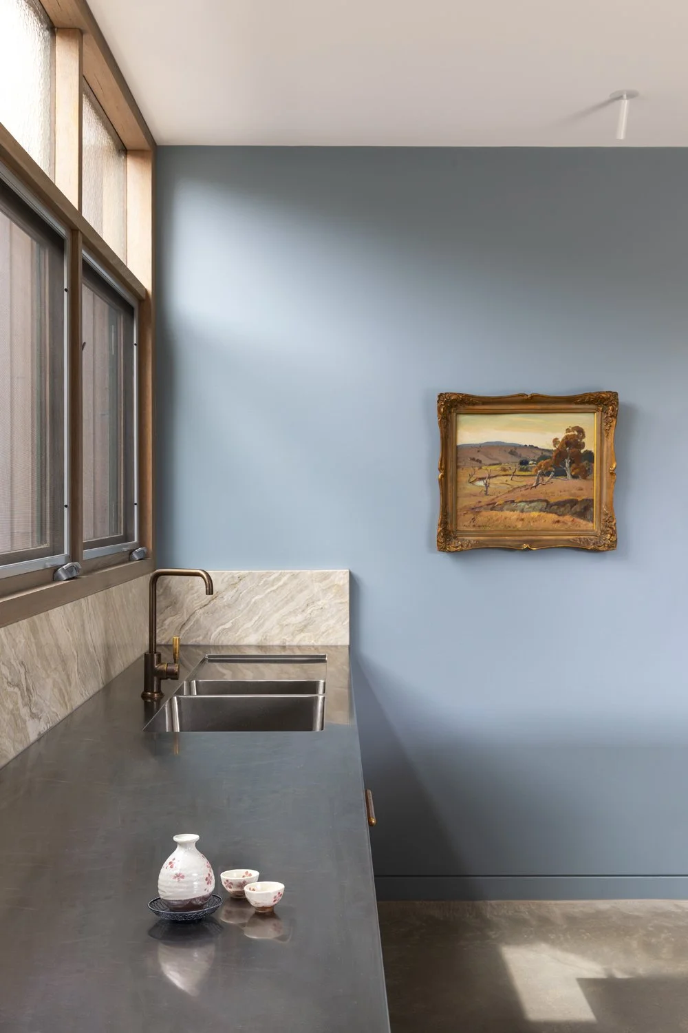 Melbourne interior designers Meredith Lee have used blue painted walls to offset artwork in this family kitchen