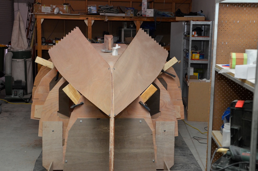 Forward panels being fitted, a couple of screws with washers attach the planks to the stem in their correct position, the wooden blocks on the frames hold the planks in place at an angle to avoid twisting the planks while screwing to the stem.
