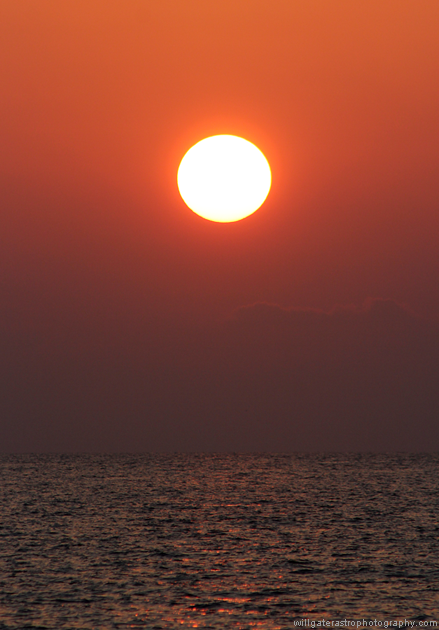 Sunset over water with reddened solar disc