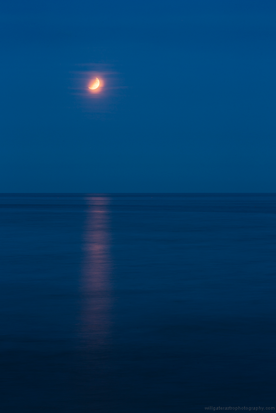 The partially eclipsed full Moon reflecting in the waters off the Jurassic Coast, UK - 16 July 2019