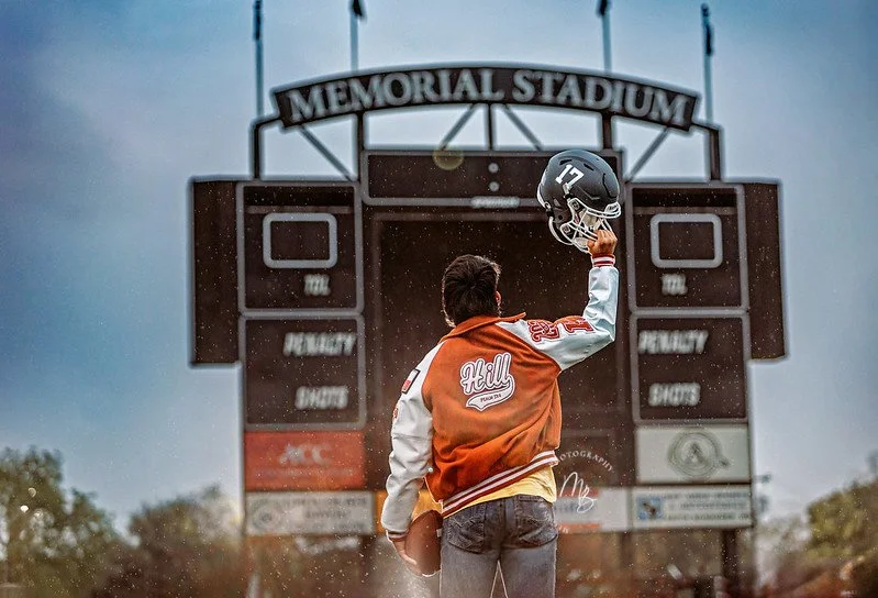 senior boy at alvin high school stadium lifting helmet overhead