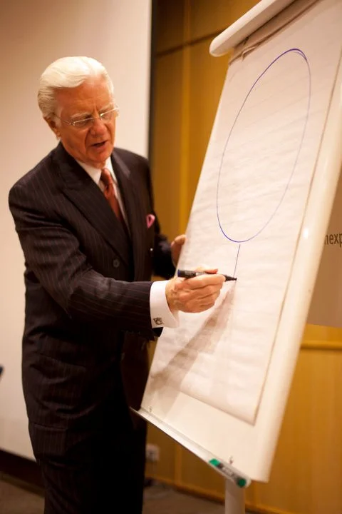Bob Proctor piirtämässä legendaarista tikku-ukkomallia perjantai-illan VIP-tilaisuudessa.