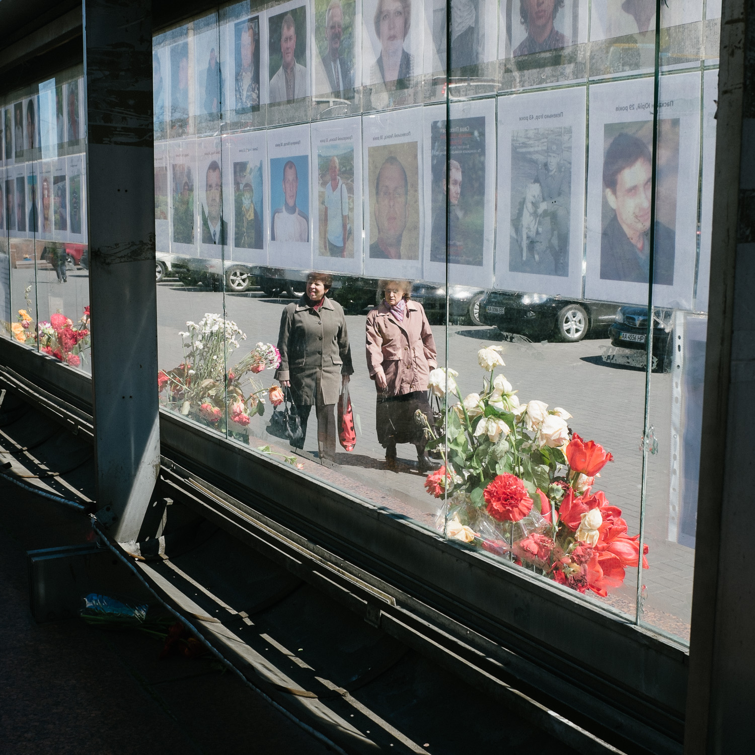  Women walk past a display of pictures of those killed in Ukraine's Euromaidan protests, April 2014. 