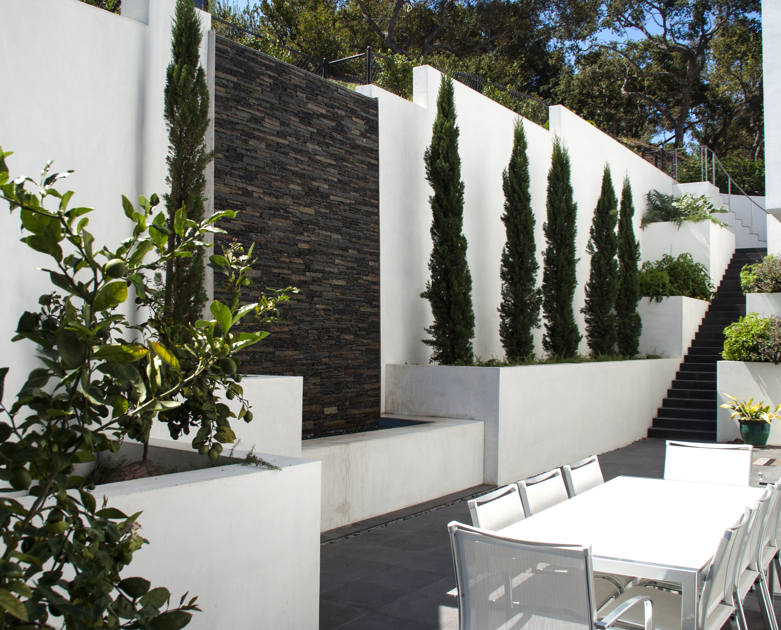 A captivating wall water feature with a striking white wall and lush green landscape make for a enjoyable backdrop for any type of gathering. 