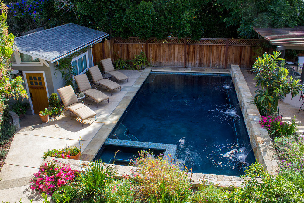Spacious medium sized pool with built in spa, stairs double as easy entry and pool bench conveniently along spa. Stone wall along back side of pool provides safety next to BBQ entertainment area and provides an opportunity for inventively pleasing triple water falls.