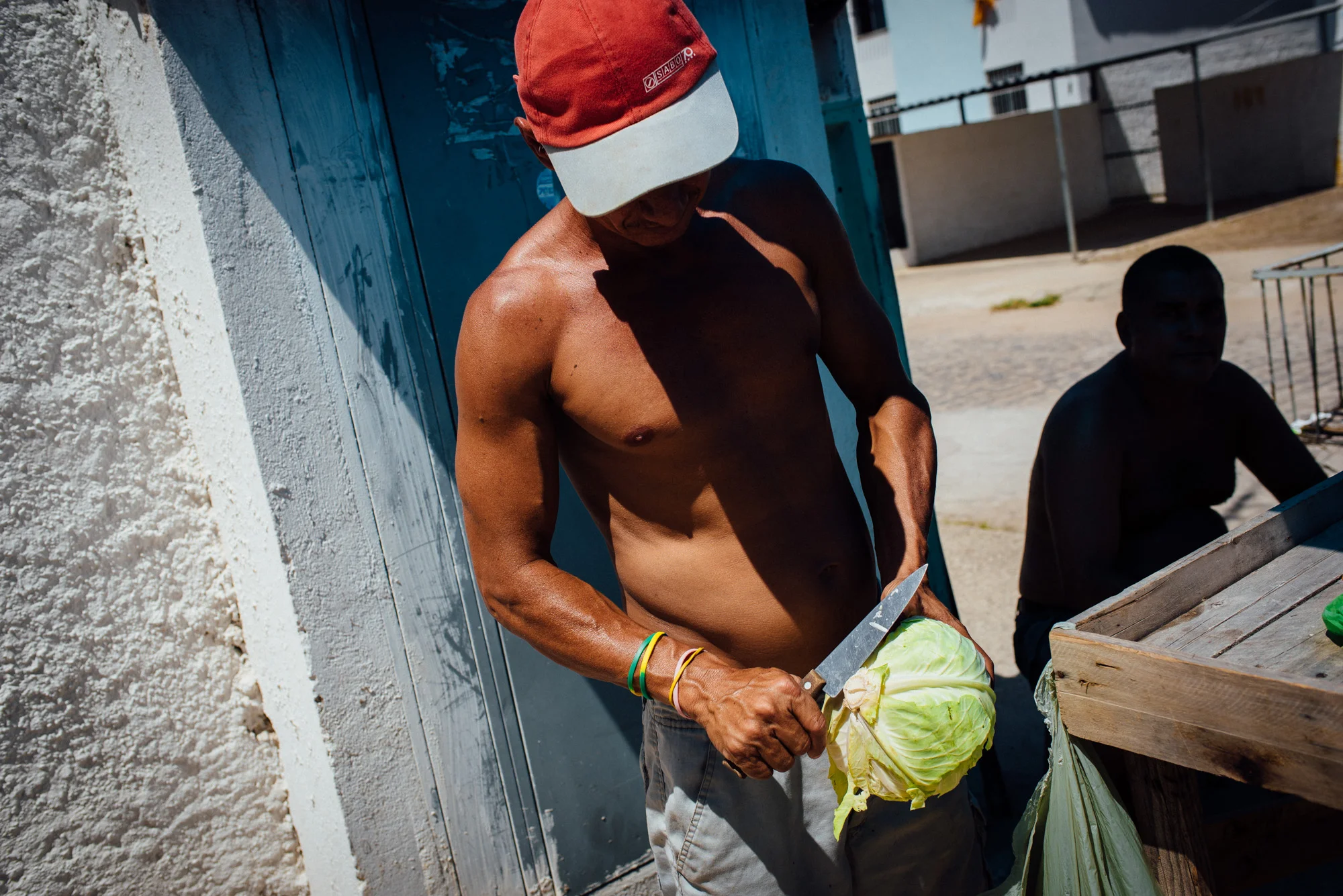 Jose Carlos, 38, cuts a head of lettuce to sell in front on his house. Some residents of the Irma Dulce housing project in Joao Pessoa, far removed from the city center, have opened up shops in front of their houses.
