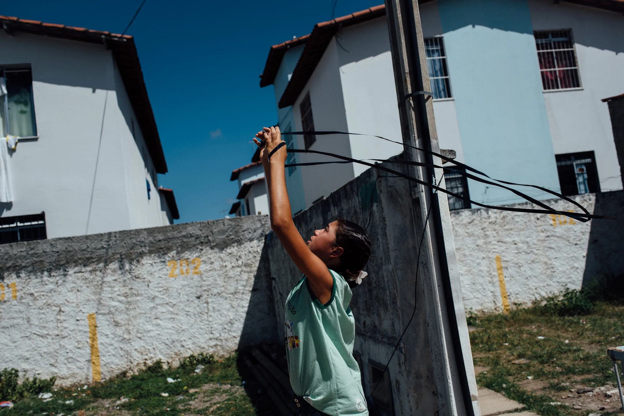 A young girl plays with a piece of VCR tape she found. There are few options for kids in a place as remote as the Irma Dulce projects.