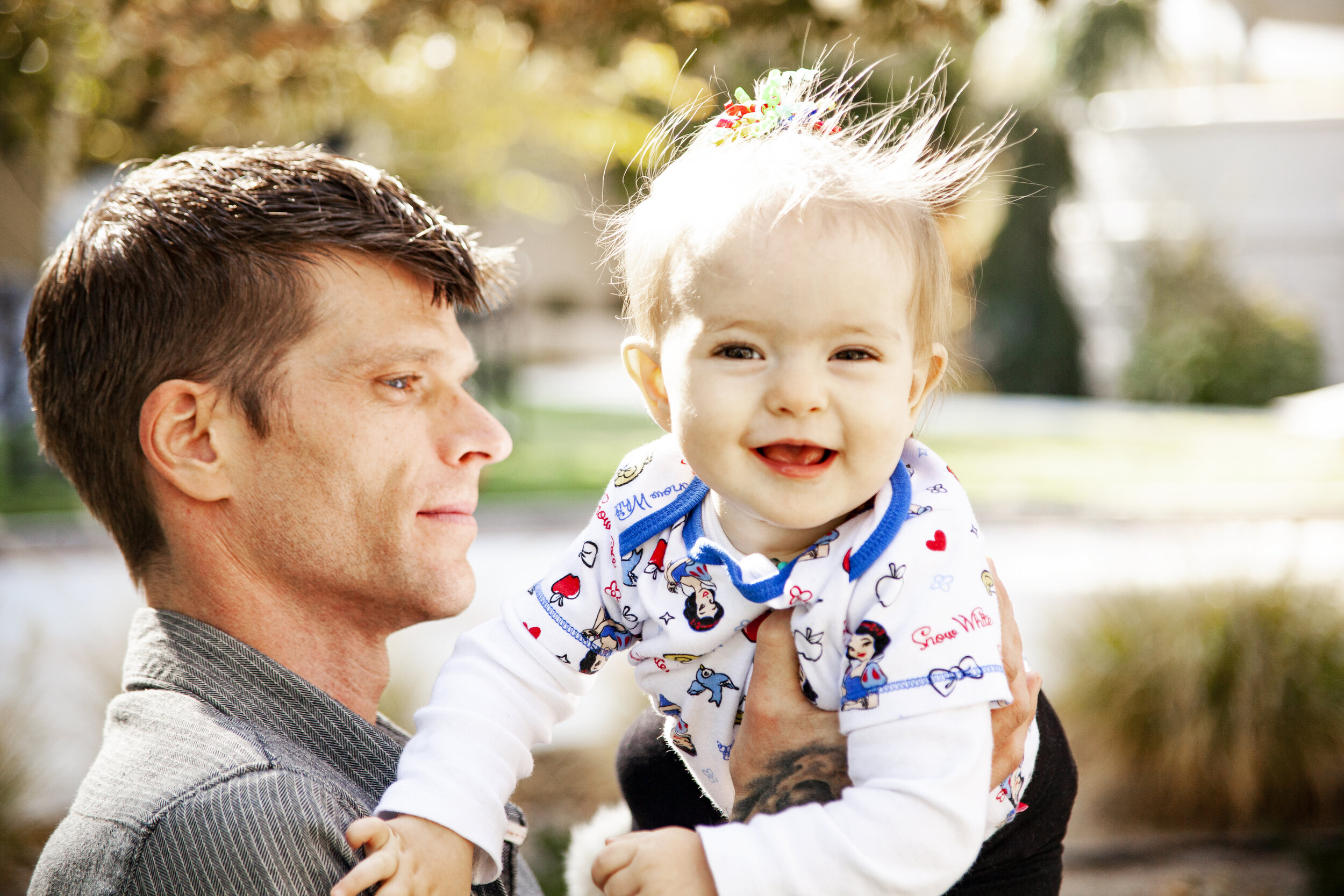 Dad holding a laughing baby during an outdoor portrait session in Reno, NV and Lake Tahoe and Carson City with natural sunlight.