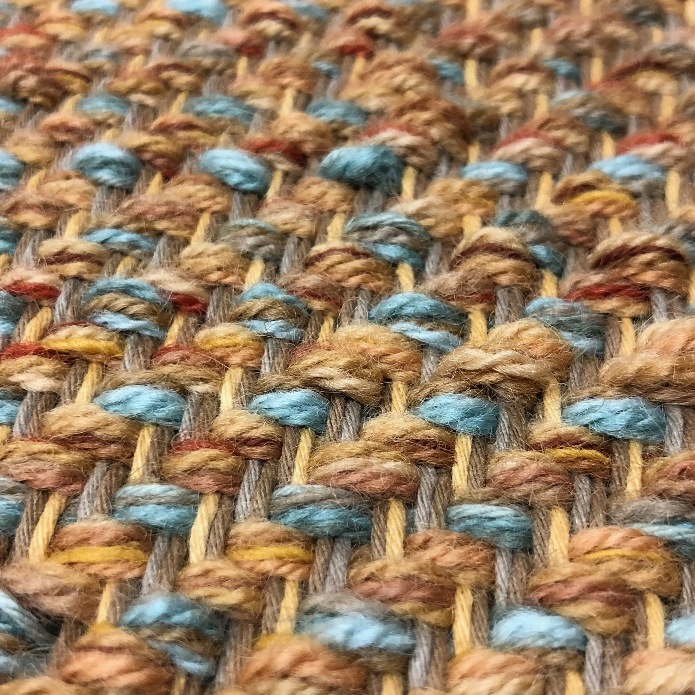 In this close-up shot of twill, you can see that there are two cotton warps (vertical in this image), each with two threads: taupe and brown, and yellow and brown. Following the wool weft (the horizontal yarn), each pick (or row) moves to the right one set of cotton warp. All the yarn is locked in place and very strong.