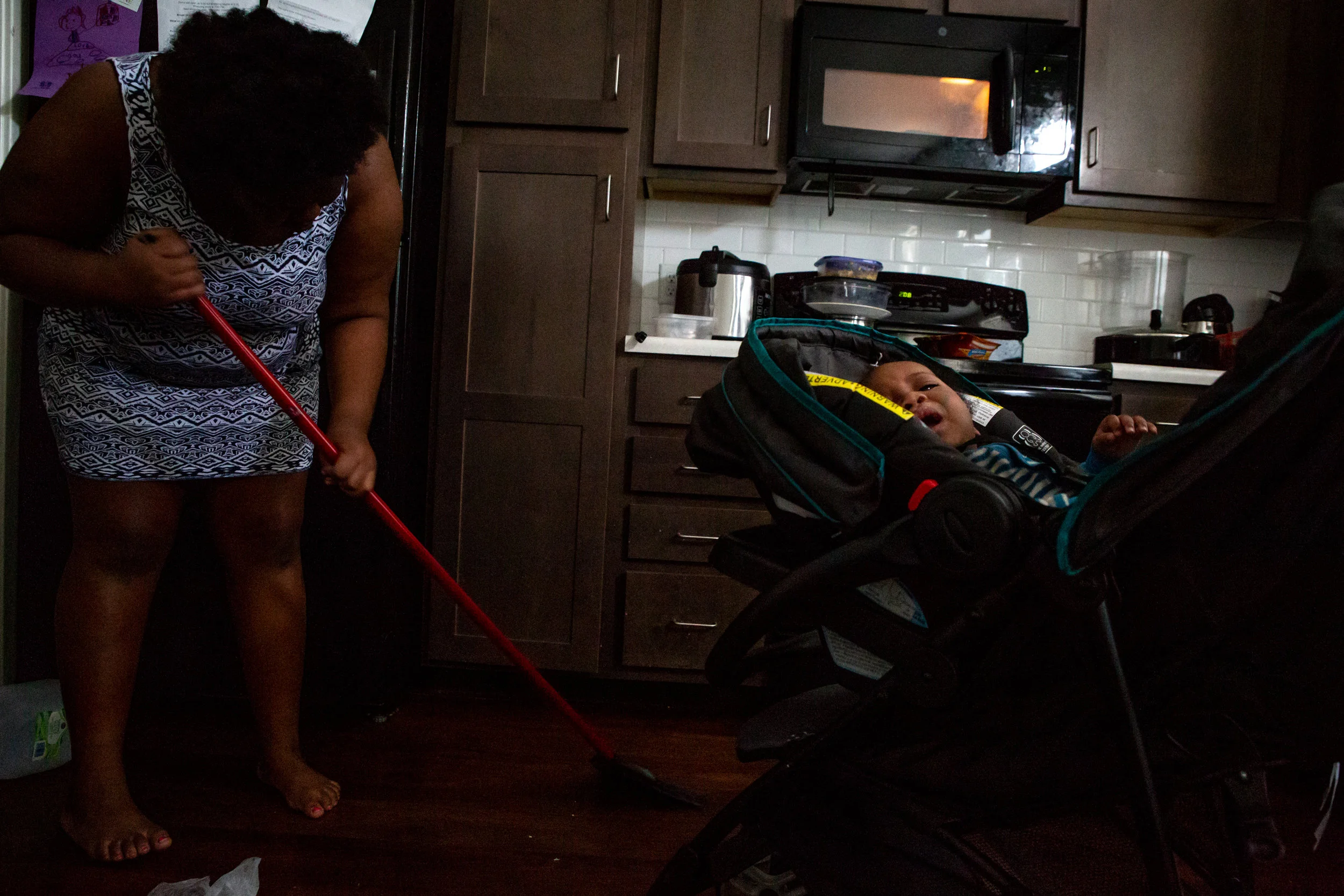 Mikelah sweeps the kitchen floor next to her son, Isaiah, on Saturday, Oct. 20, 2018. “I’m like the second mom in here,” she said of her responsibilities around the house and taking care of her siblings. Mikelah’s stepfather works nights and sleeps during the day, when her mother works as a city bus driver.