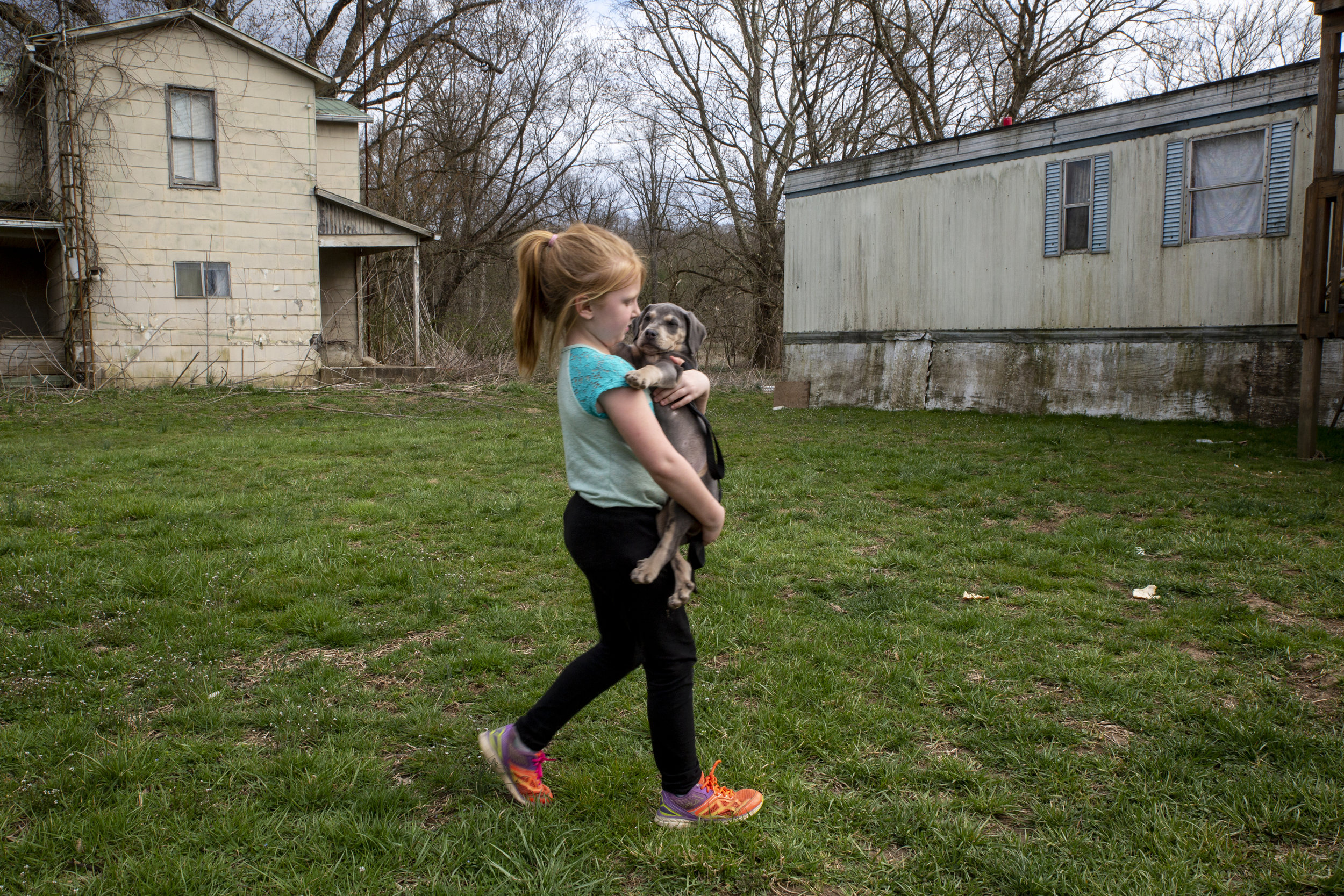  Brooklyn Roof, 6, walks toward her family’s trailer holding their new puppy, Chocolate. Many of the community’s oldest buildings have been abandoned, but stand alongside the few remaining inhabited homes because it’s costly to tear them down. 