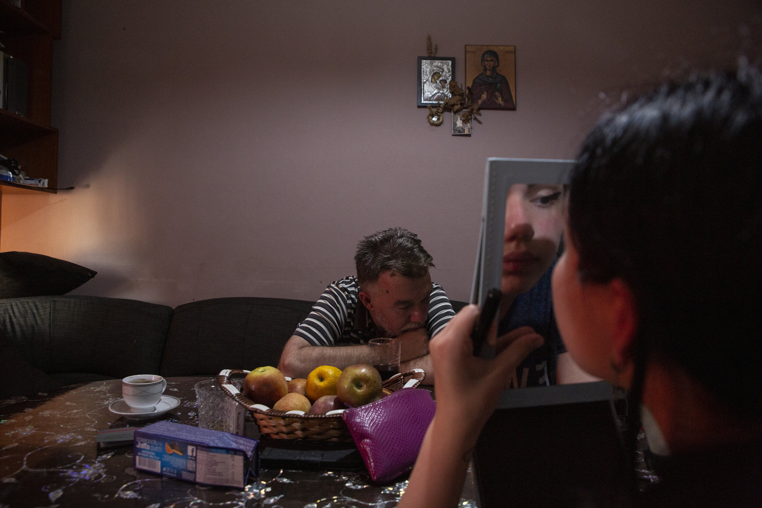  Aleksandra Vajsel, 15, applies makeup at the kitchen table  across from her father before going to meet friends at a cafe in the Serb-majority side of the city, north of the Ibar River. 