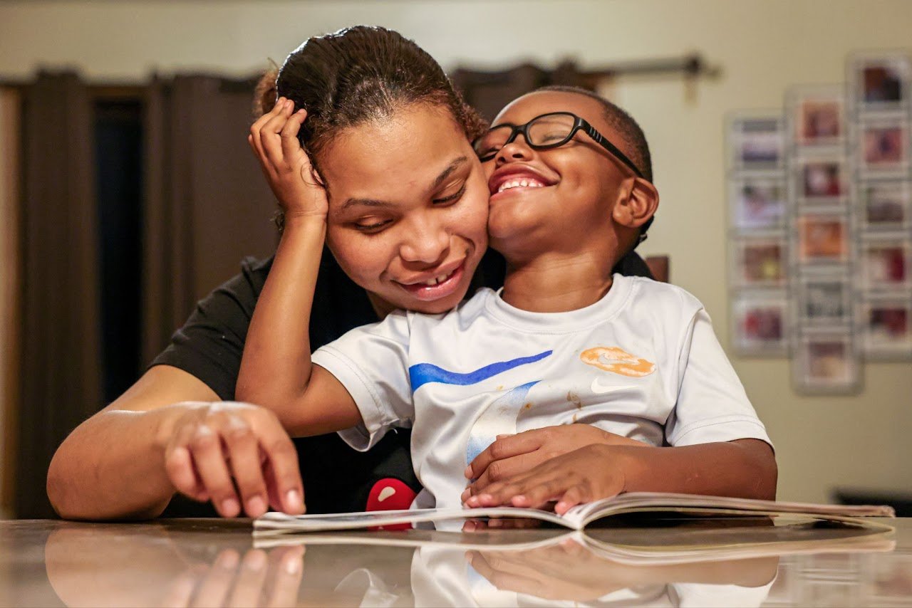  Carter hugs his mom, Carlese Overton, 26, while reading a bedtime story at the dining room table at home. Carlese has been living with her son and mother, who is Carter’s legal guardian, since she was released from jail in July 2023. Since her locat