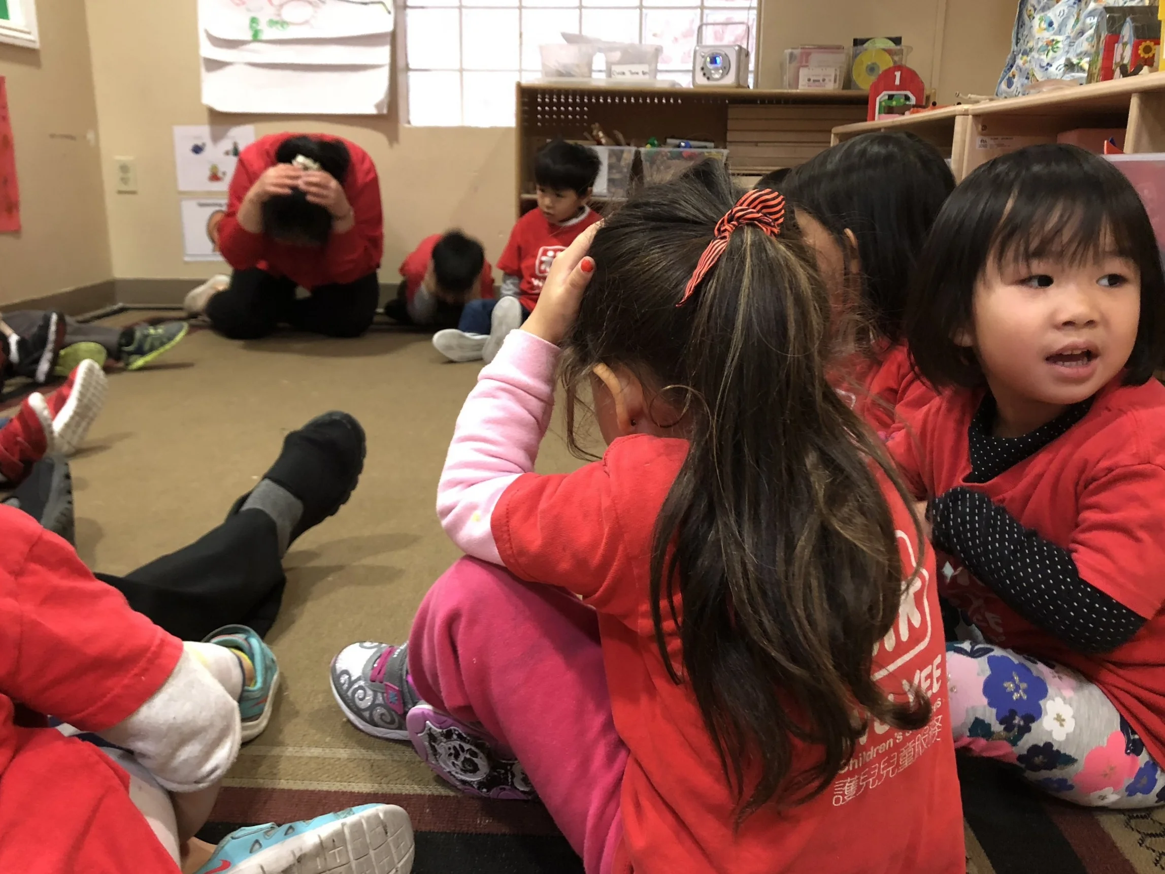 A teacher demonstrates how to protect one's self in an earthquake to the children at Wu Yee Children's Services Lok Yuen Child Development Center