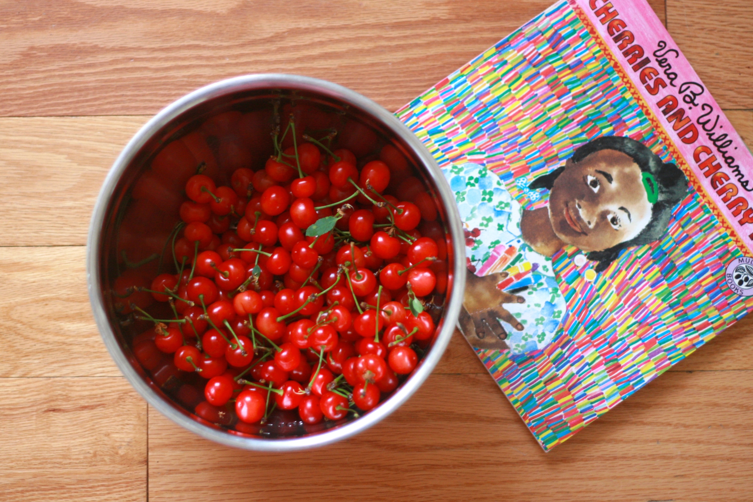 Some of our backyard cherry spoils, plus our family's favorite cherry-themed book, Cherries and Cherry Pits