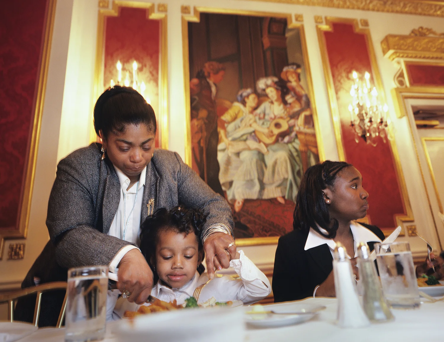 A volunteer instructor from the Development and Finishing School assists a young lady in a table etiquette exercise, Plaza Hotel, New York, NY, 2004