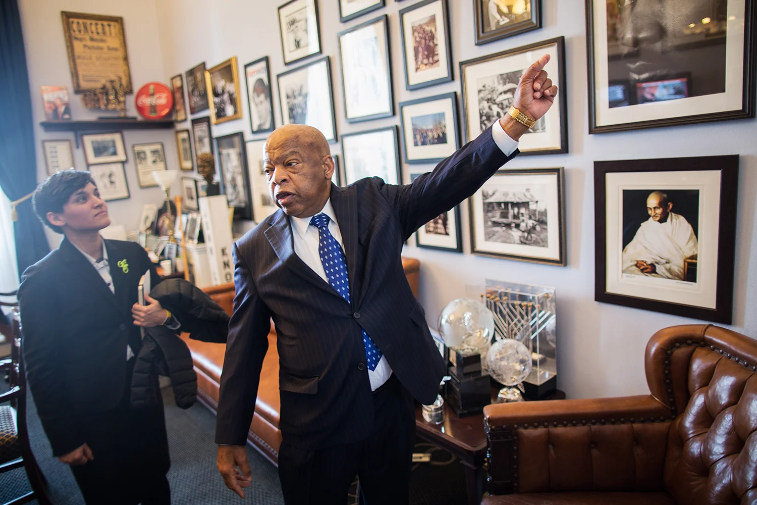 Congressman John Lewis (D-GA, 5th District), shows photographs on his wall to visiting member of the League of American Bicyclists, Washington, DC, 2014