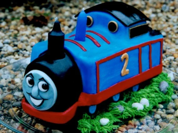 Thomas with the two candles as part of the train cake design, for a second birthday