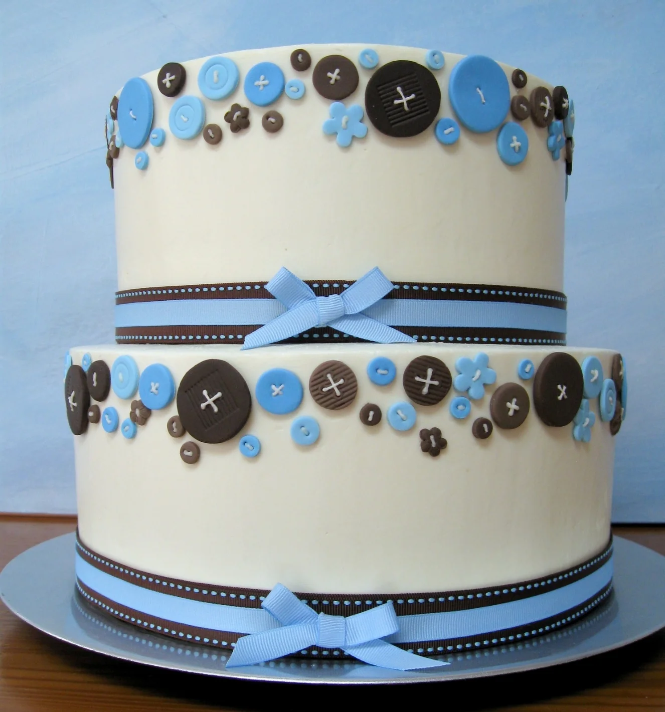 Fondant buttons and ribbons decorate this buttercream baby boy shower cake