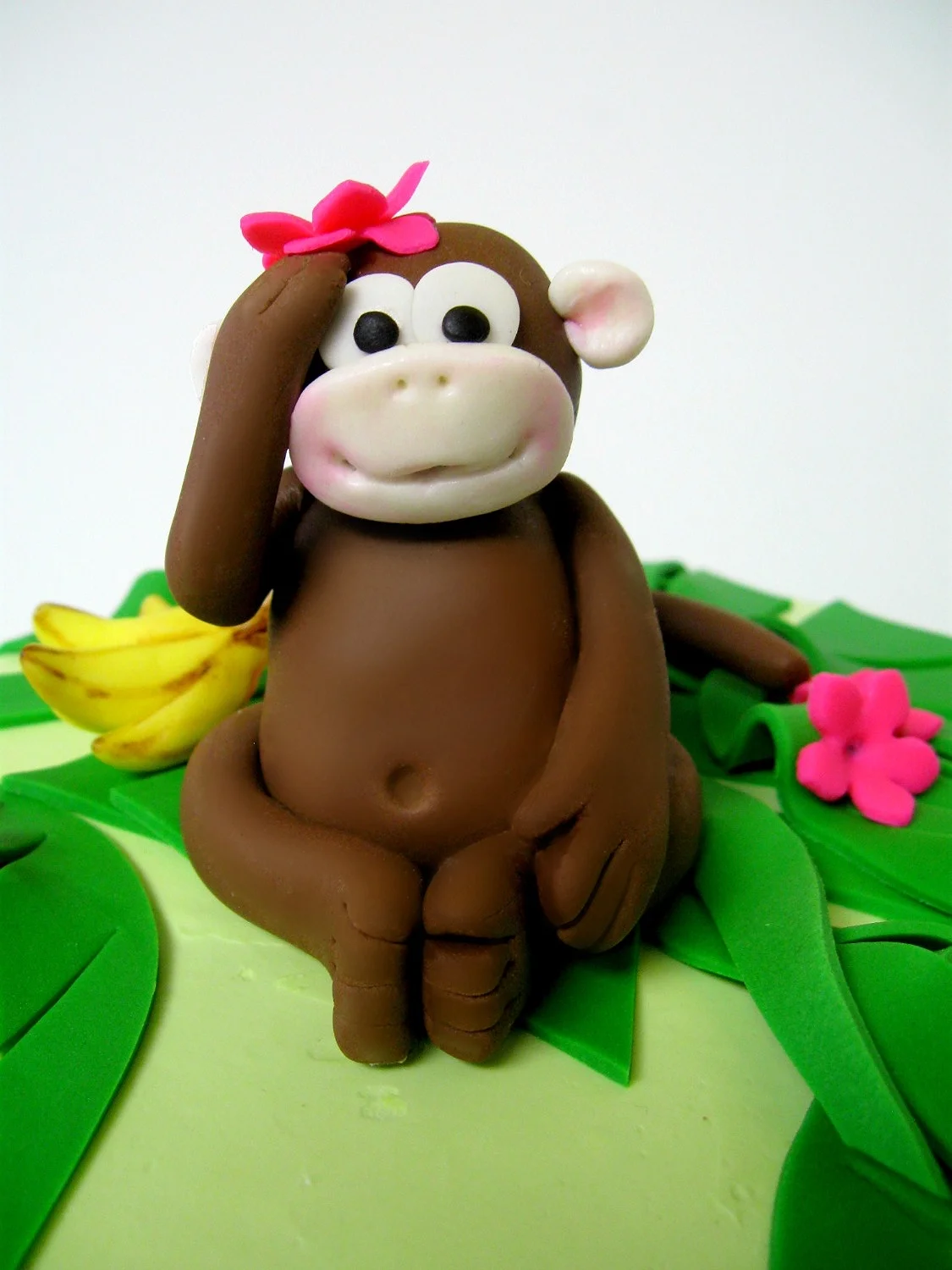 Fondant monkey, bananas, flowers and palm branches top a buttercream cake