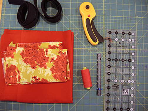 Materials clockwise from top: rotary cutter, omni-grid ruler, seam gauge, thread, fabric, webbing