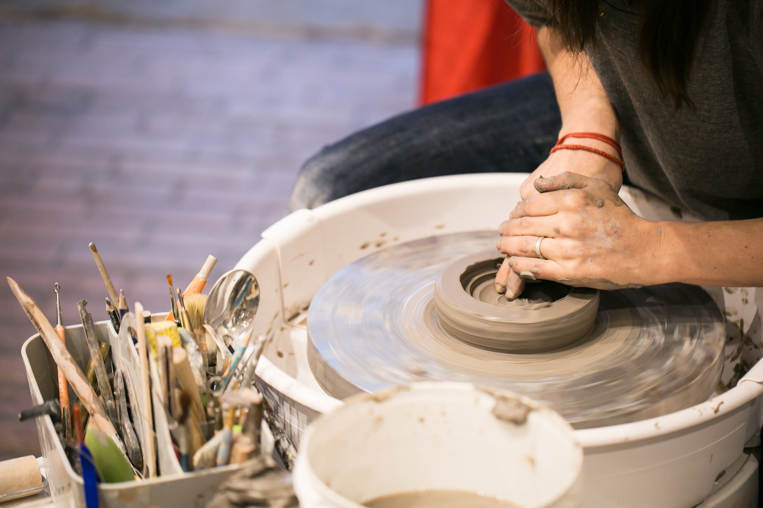 Potters hands are making a bowl with clay at a potters wheel