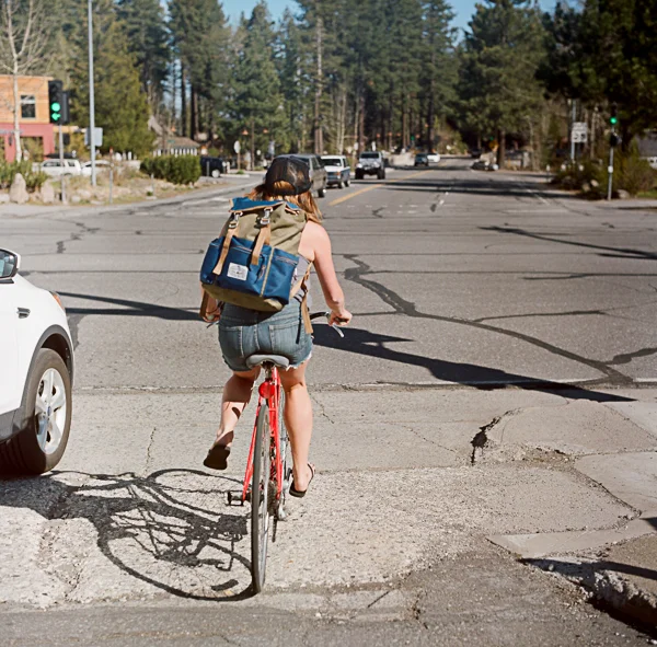 A woman riding a bicycle on a street in a small town with trees and buildings in the background during daytime.