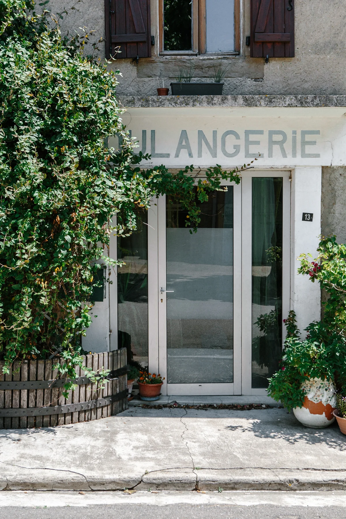 Storefront with a sign that reads 'Lingerie', glass door, and surrounding potted plants and shrubbery.