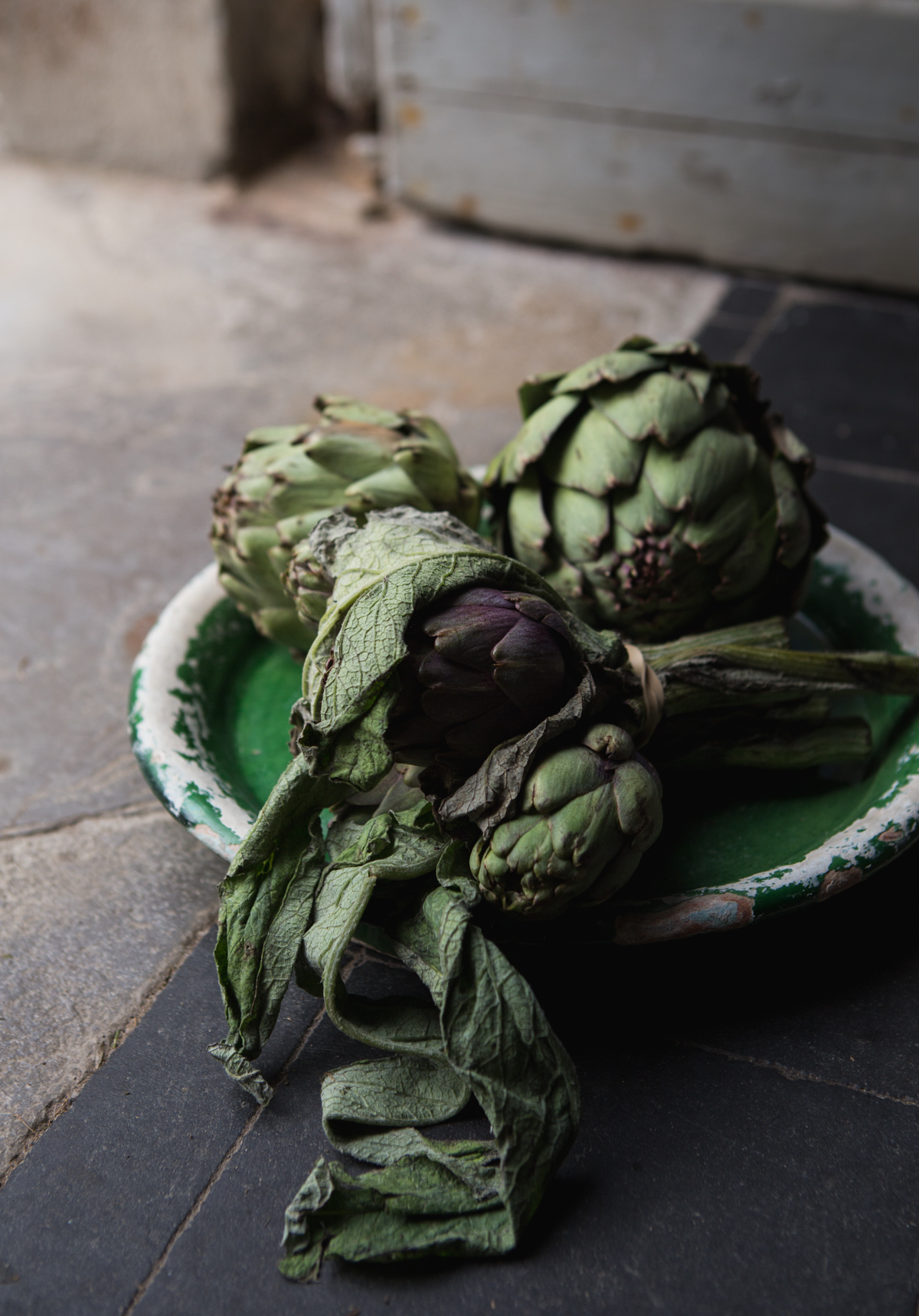 Dried and wilted artichokes in a bowl on a tiled surface.