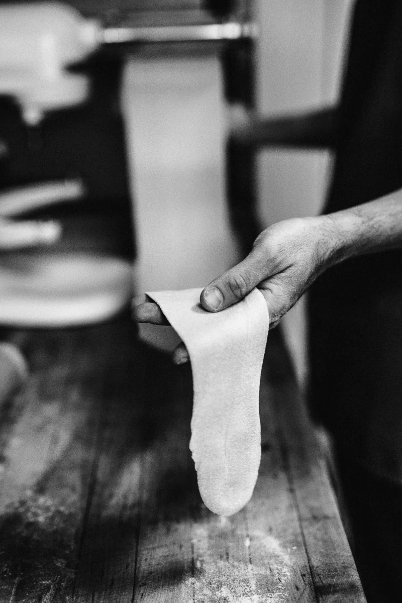 A person holding a sock, which is hanging down, in a room with wooden flooring and furniture.